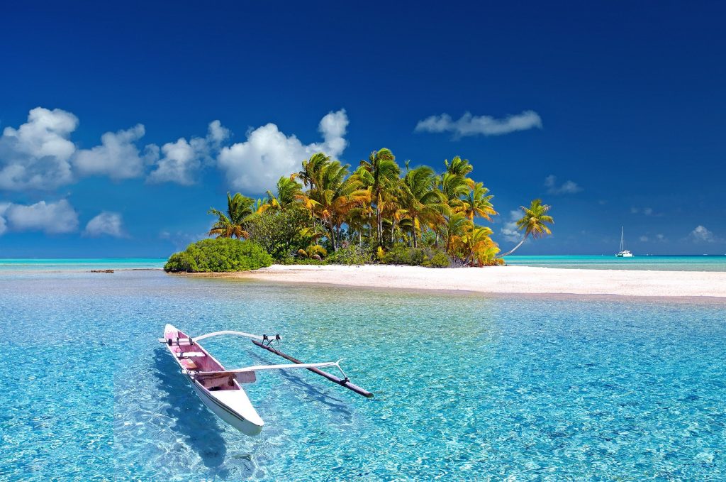 A vibrant tropical scene with a clear blue sky, turquoise water, a white sandy beach, and lush green palm trees. a traditional canoe is moored near the shore, and a sailboat is visible in the distance.